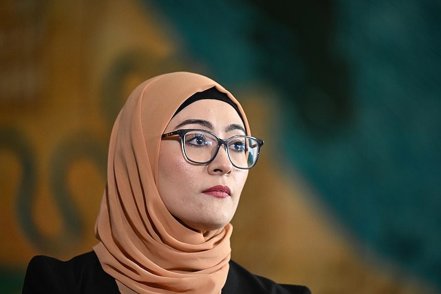 Fatima Payman headshot, serious expression wearing glasses and a tan-coloured hijab