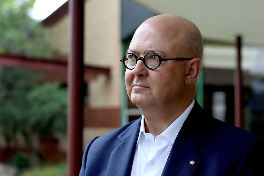 Williams wears black rimmed glasses at his home, looking outward to some greenery