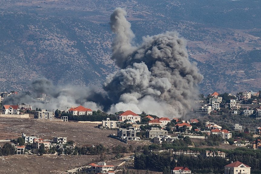 A plume of grey smoke rises from a town.