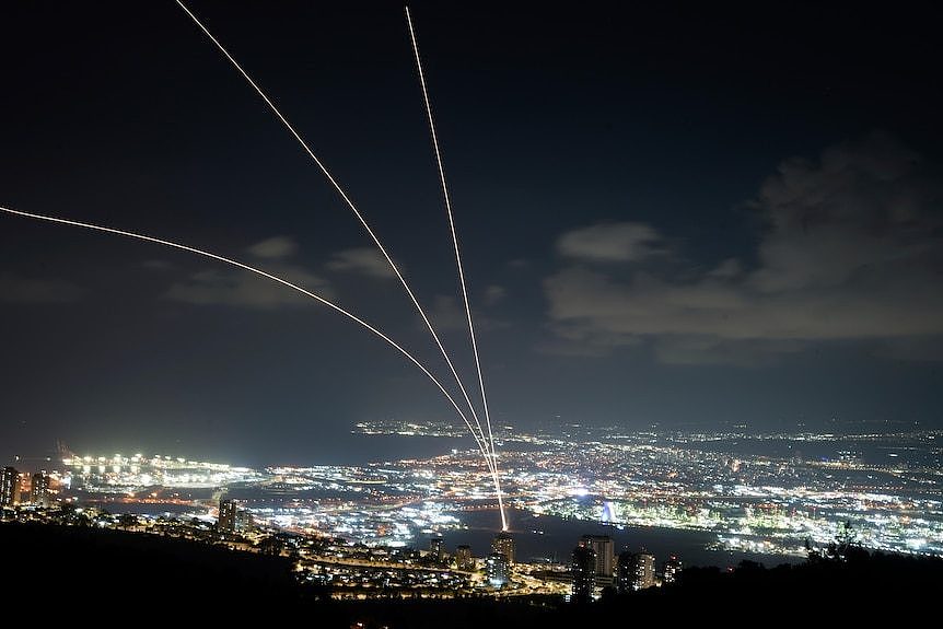 Streaks of light from rockets over the night sky of a city. 