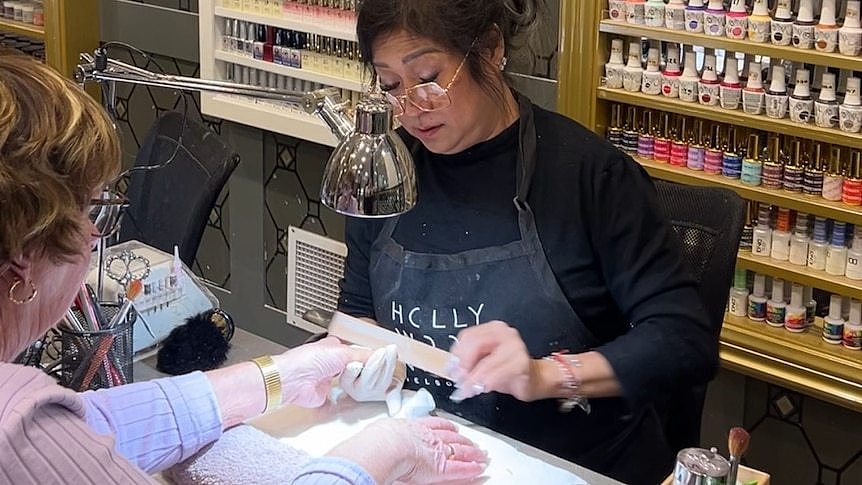 A woman sits in a chair while her nails are filed at a salon in Melbourne.