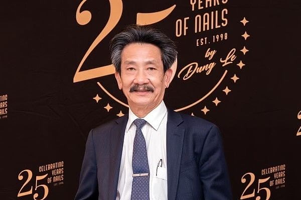 A Vietnamese man picture in a navy blue suit and tie at a gala event