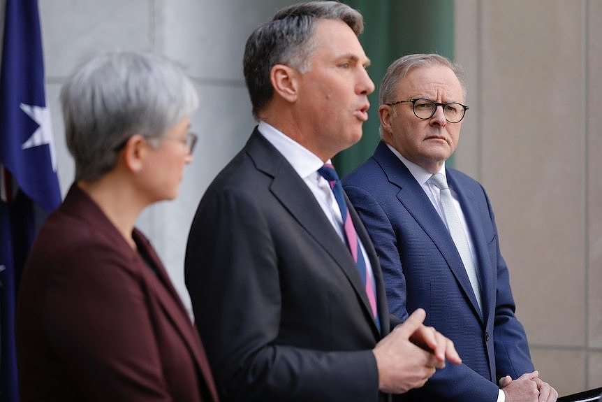 Wong, Marles and Albanese stand at lecterns in a courtyard speaking.