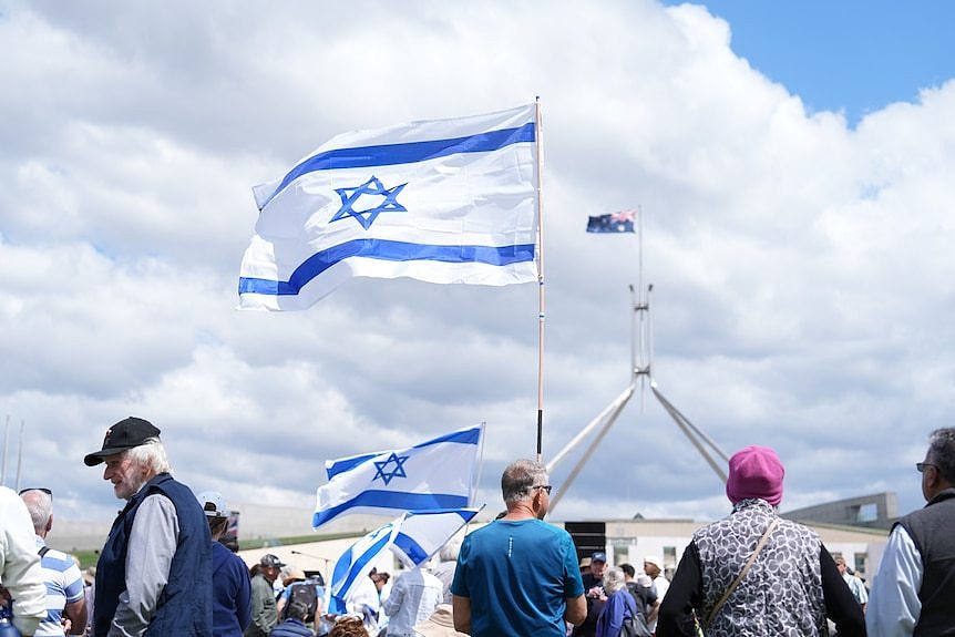 People gathering outside Parliament, holding Israeli flags