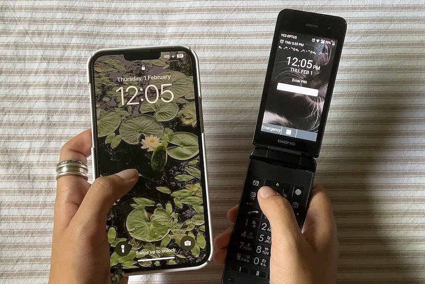 A close up of a person's hands, one holding an iPhone and one holding a small flip phone.