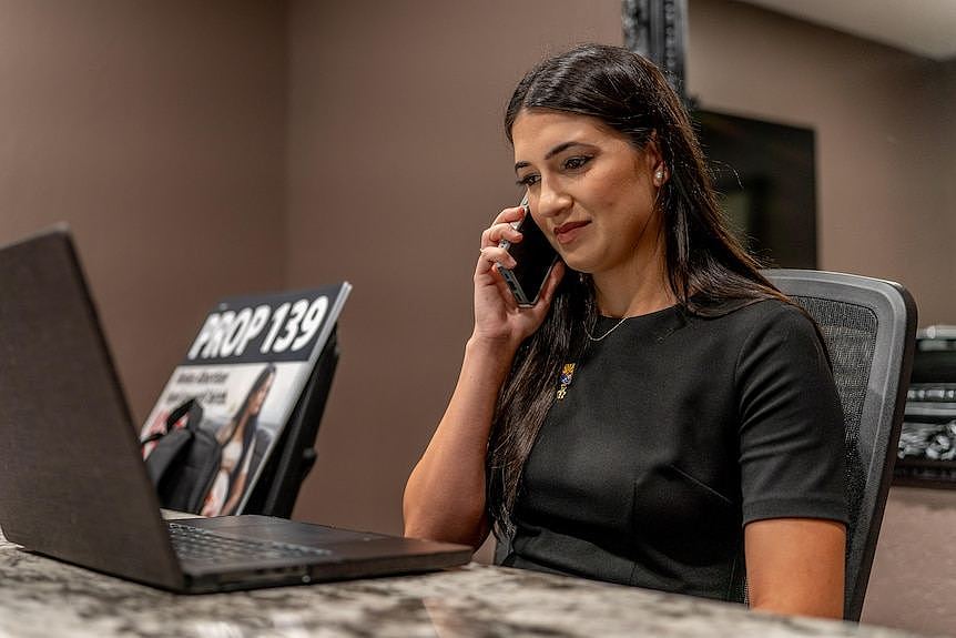 A woman with dark hair holds a phone to her ear 