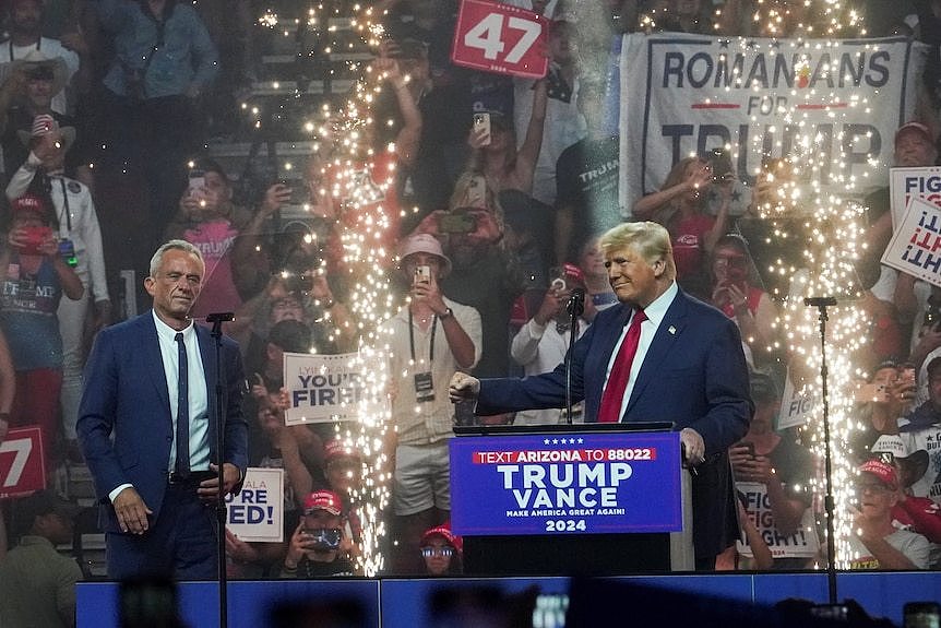 A man stands on a stage surrounded by fireworks.