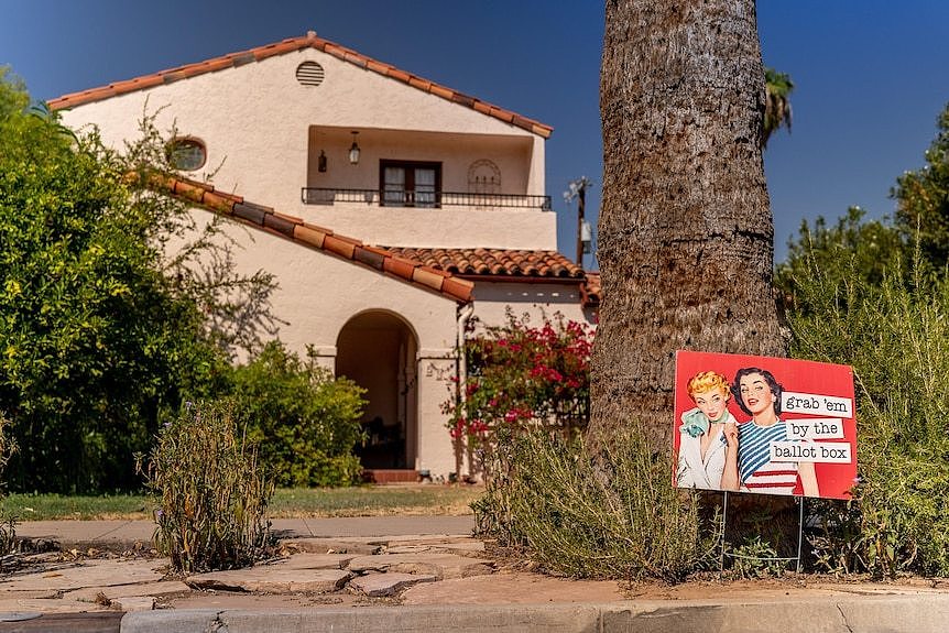 A sign outside a house depicts two women and says 'grab 'em by the ballot box'