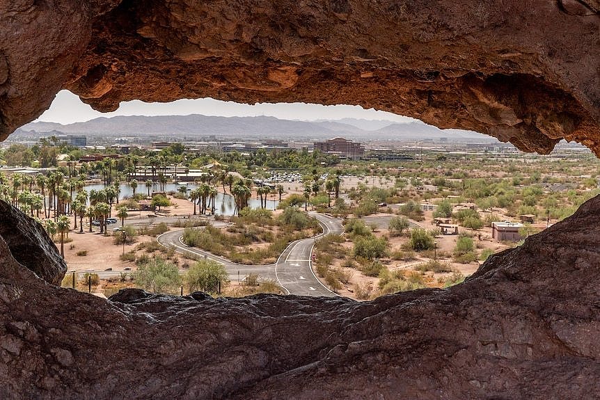 A city skyline in a desert setting, seen through an opening in rock.