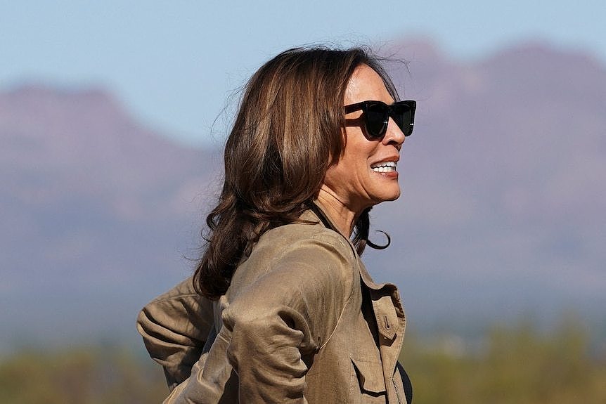 A woman with dark hair in sunglasses and a camel jacket