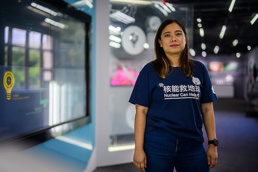 A woman with long hair, blue shirt that says Nuclear Can Help