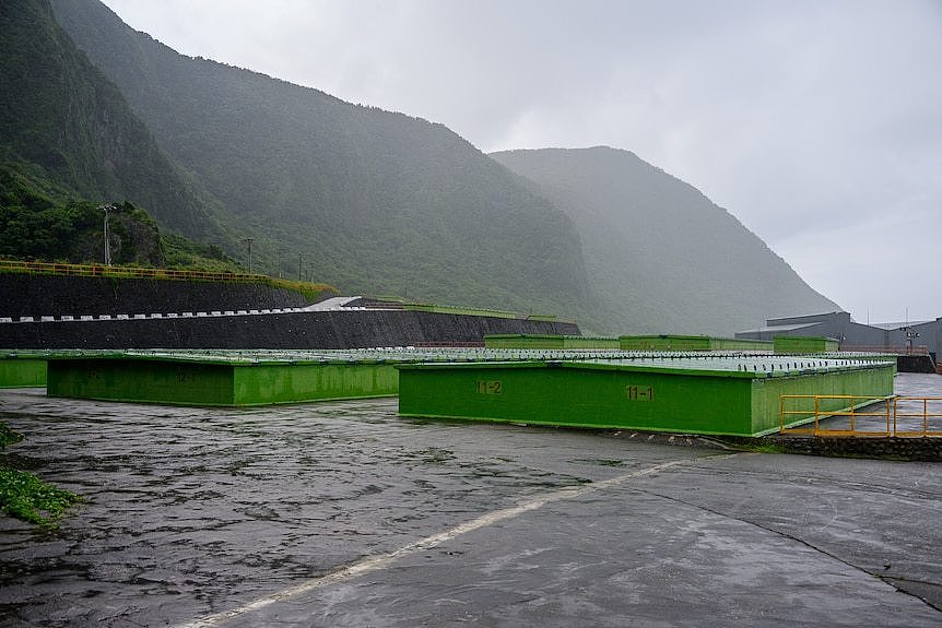 big green containers in an open land on the side of a mountain