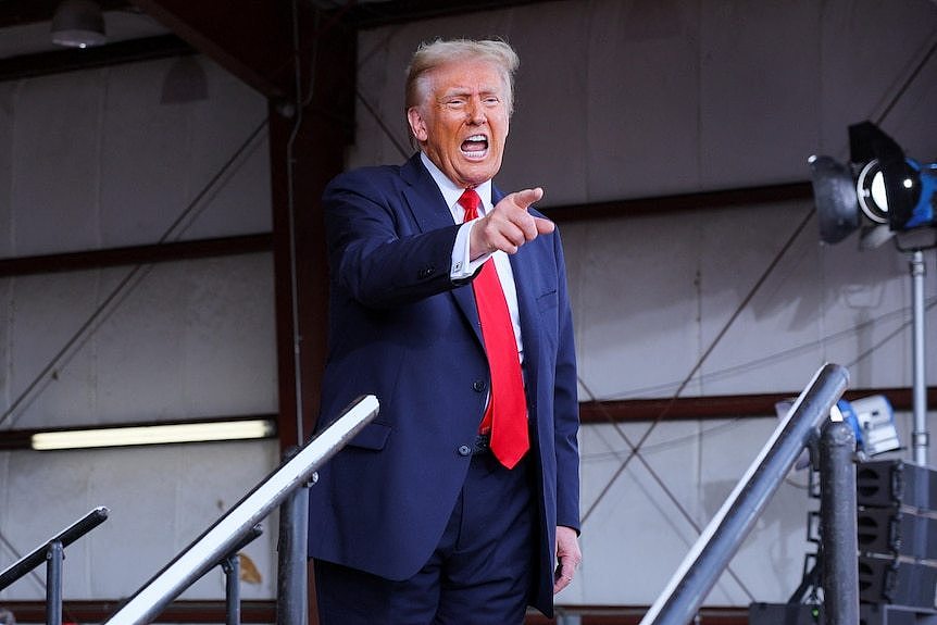 Donald Trump puts his finger in an aircraft shelter