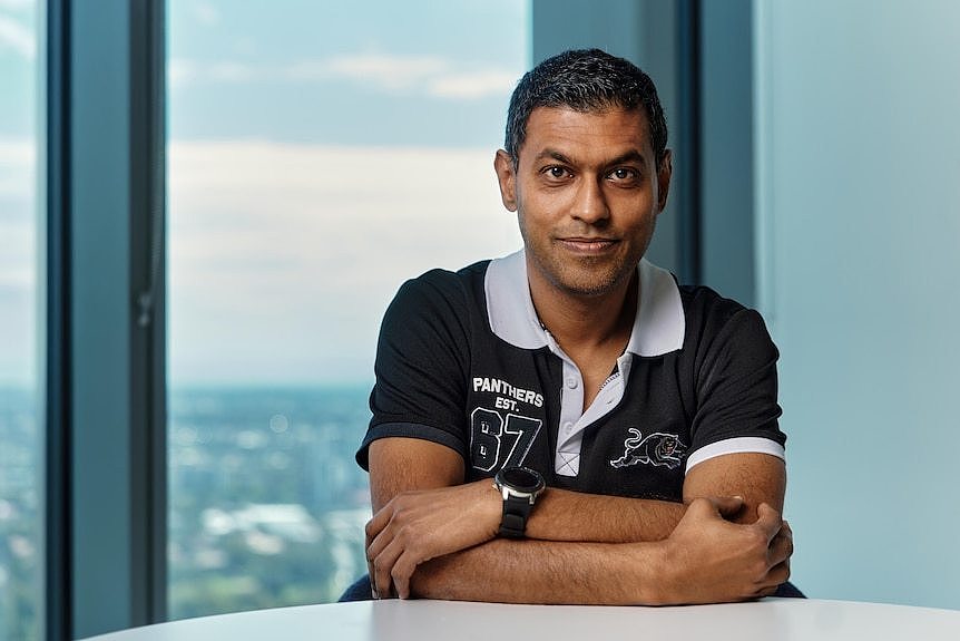 Ravitesh Lal sits with his arms folded at a desk.