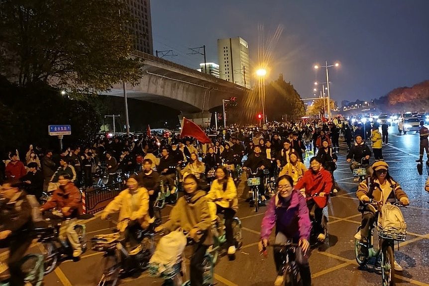 Chinese cyclists bike towards the camera with smiles.