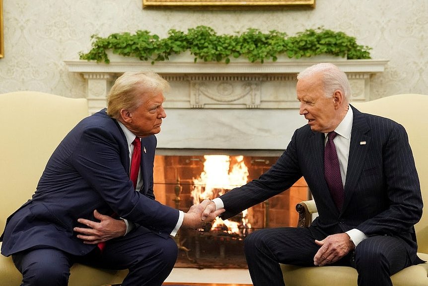 Donald Trump and Joe Biden sit in the Oval Office and shake hands.