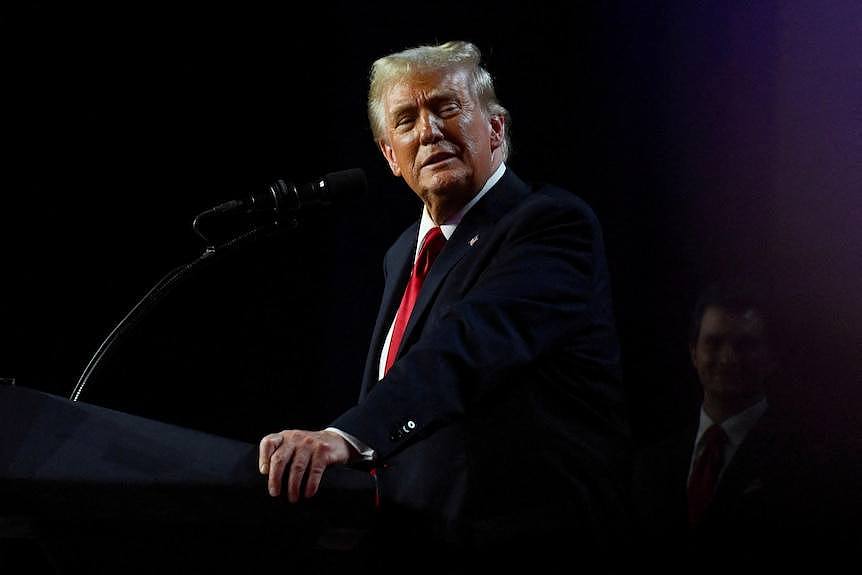 Donald Trump looks sideways while standing at a podium 