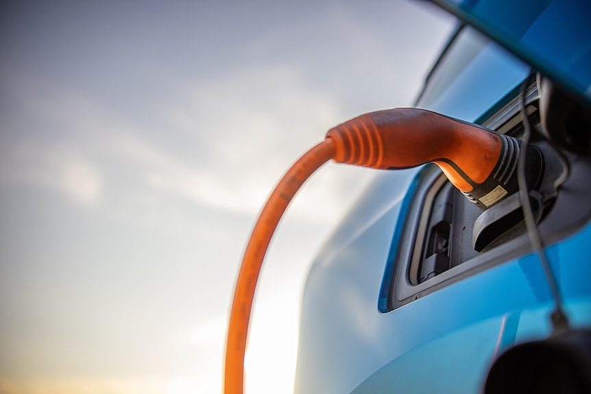 A close-up of an orange electricity cable plugged into a car.