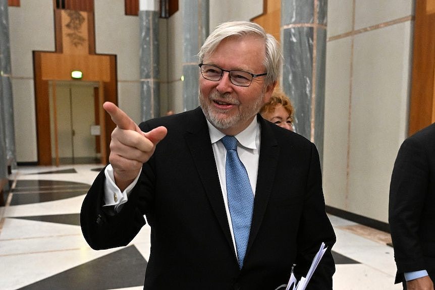 Kevin Rudd smiles and points as he walks through the marble foyer of parliament house.