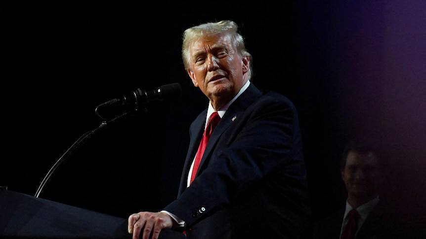 Donald Trump looks sideways while standing at a podium 