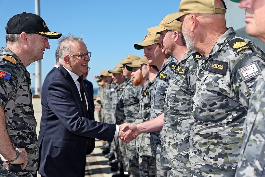 Anthony Albanese shakes hands with people wearing camo. 