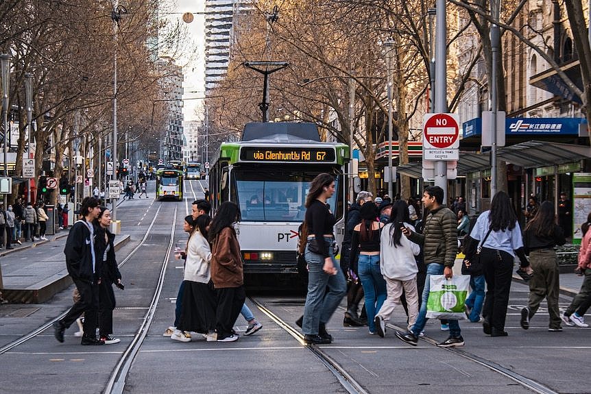 A shot of a busy Melbourne street with pedestrians in front of a tram.