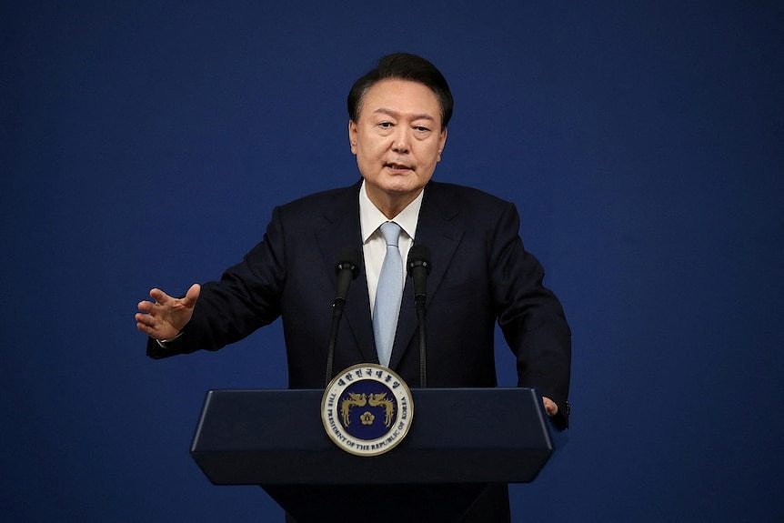 The South Korean president standing behind a lectern in a media briefing room.