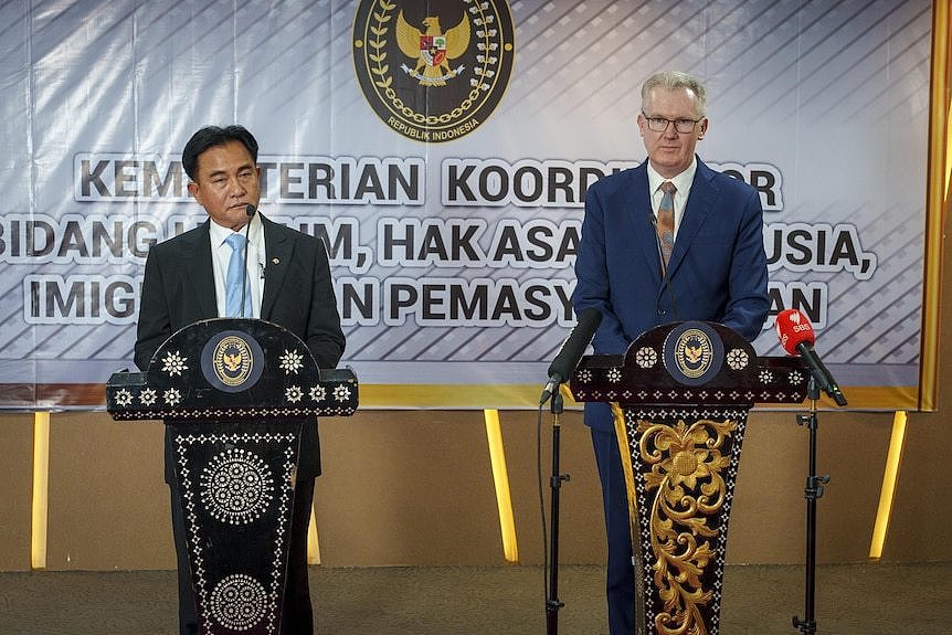 Two men in suits stand behind ornate podiums 