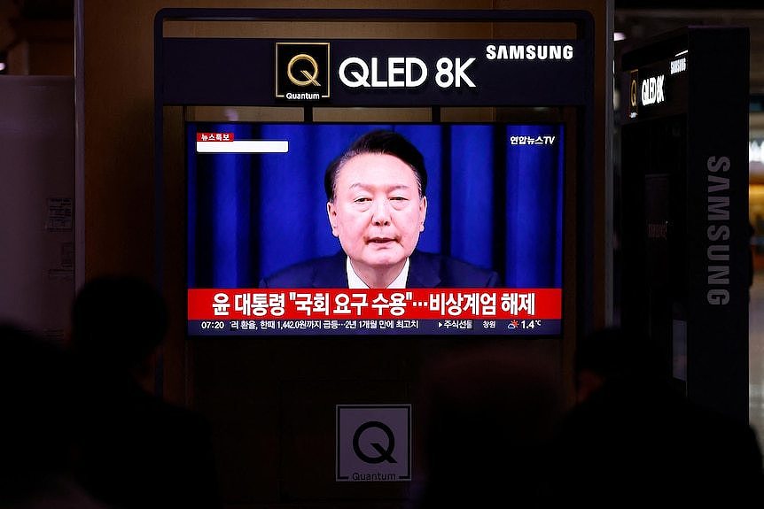 A tv screen showing a man speaking on the news 