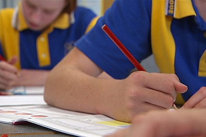 Generic TV still of 2 anonymous students writing at school desk at unidentified Qld primary school.