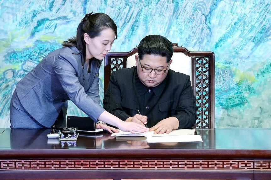 A North Korean woman in her 30s helps a North Korean man in his 30 sign a document