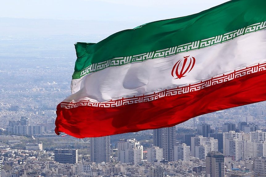 Iran's national flag waves as the streets of Tehran are seen in the distance.