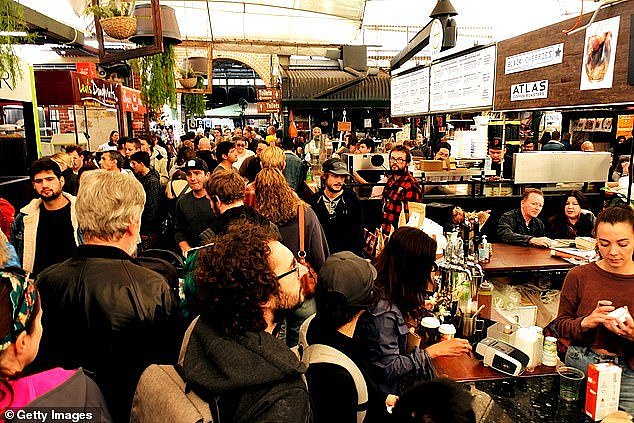 Authorities have warned anyone with cold or flu-like symptoms to stay at home and to wear masks in crowded public settings. Pictured are crowds at Fremantle Markets