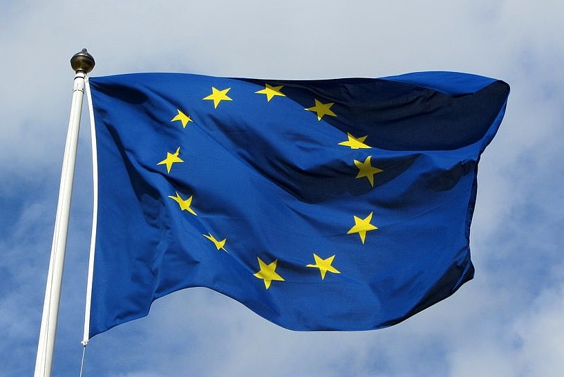 European Union flag against a cloudy blue sky.