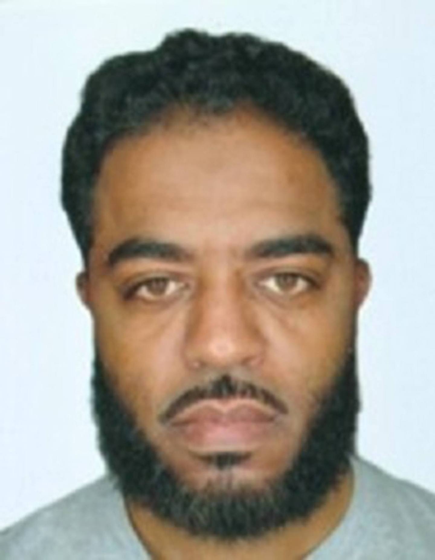 A passport photo of a bearded man with a neutral expression.