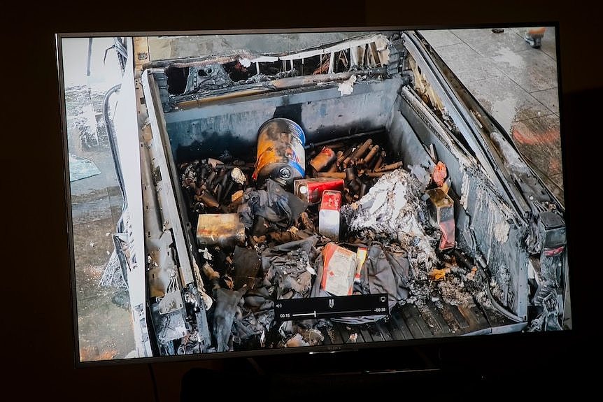 The burnt tray of a cybertruck contains fuel cans and other debris