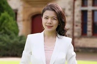 A woman in a white jacket smiles at the camera.