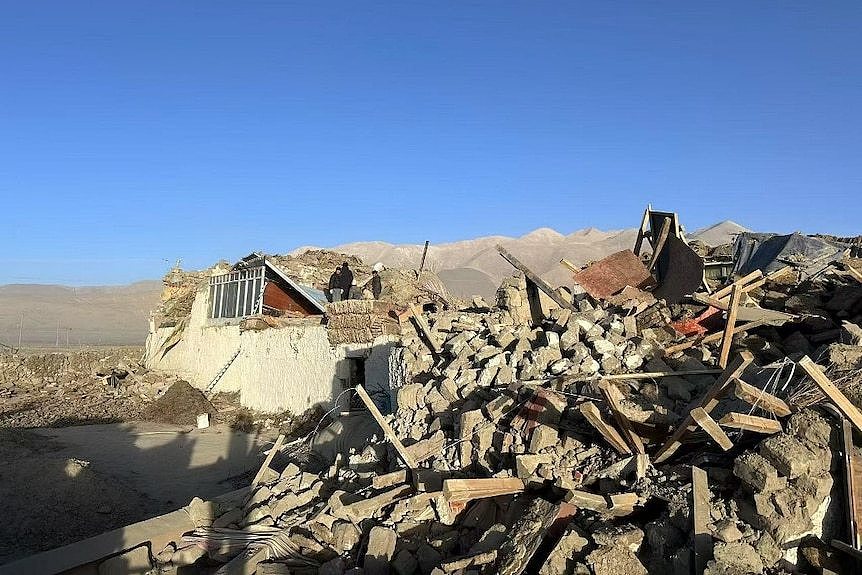 A destroyed house surrounding by building debris 