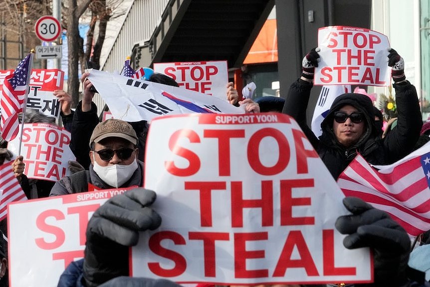 Supporters of the South Korean President hold signs saying 