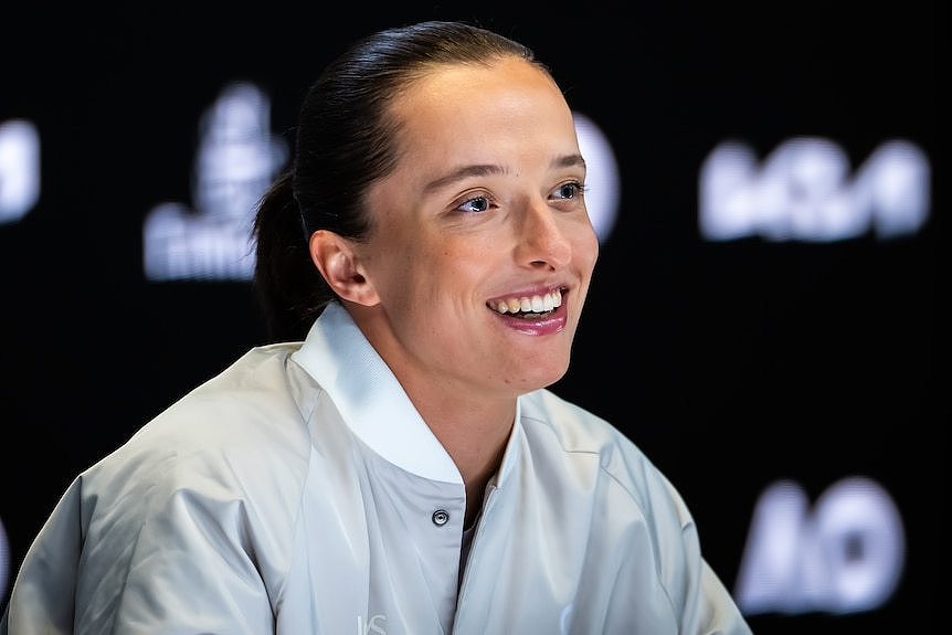 Iga Swiatek is sitting and smiling during a press conference before the Australian Open