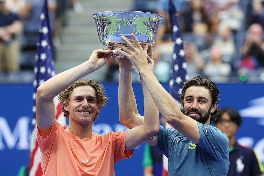 Max Purcell and Jordan Thompson hold a large silver trophy above their heads