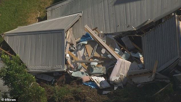 One person has been taken to hospital in a stable condition following the landslide as crews from the SES work to clear the area (the damaged home is pictured)