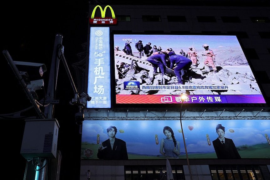 A giant screen shows footage of rescue crews in operation after an earthquake struck Tibet.