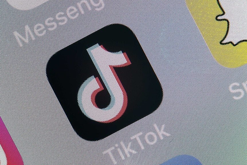 A close up of the TikTok logo on a phone screen. The logo looks like a musical note on a black background.