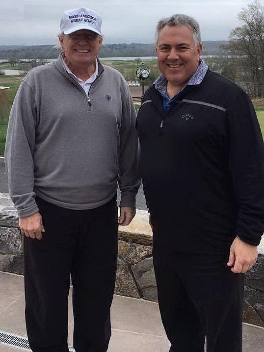 Two men, one wearing a white cap and one with salt-and-pepper hair - stand next to each other grinning at the camera