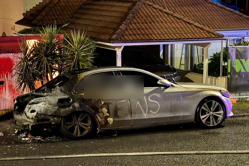 A burnt out car in a suburban street.