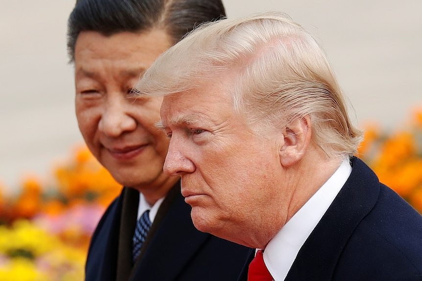 Donald Trump frowns as he looks off camera while Xi Jinping stands behind him.