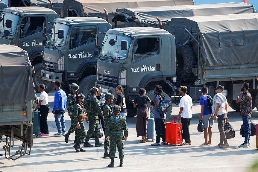 Victims of scam centres in Myanmar line up to get into Thailand army trucks