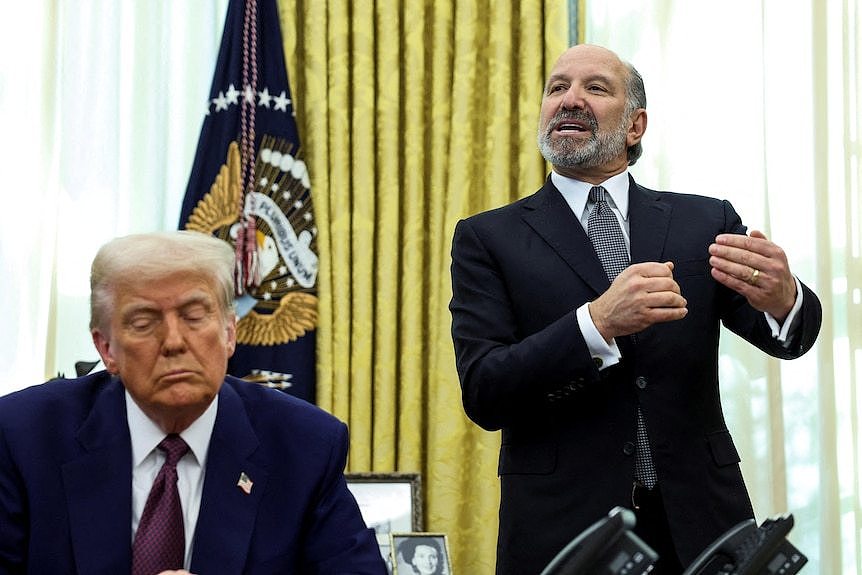 us president donald trump sits in front of howard lutnick in the oval office