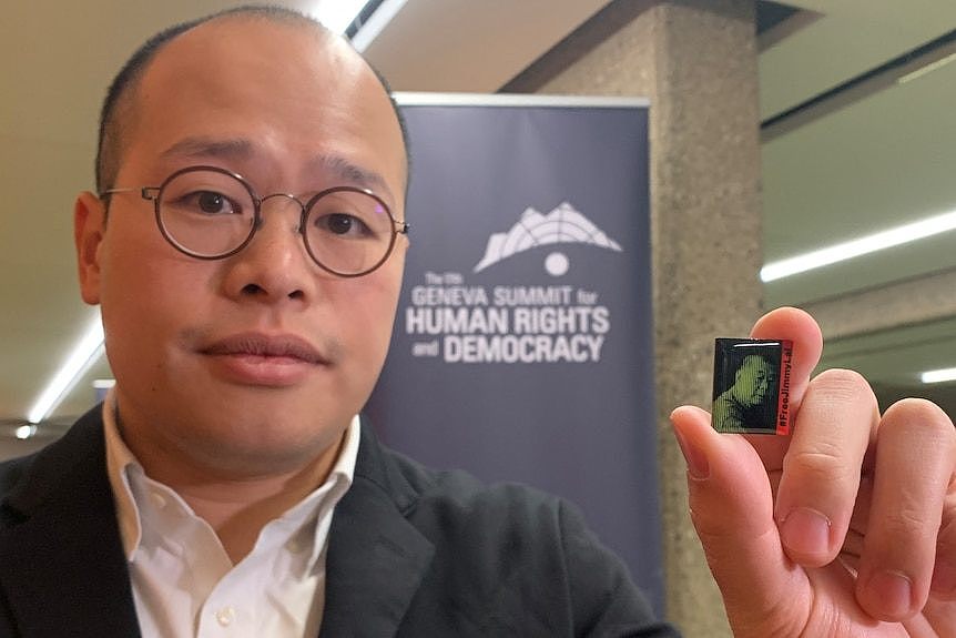 Sebastien Lai holds a pins with a portrait of his father